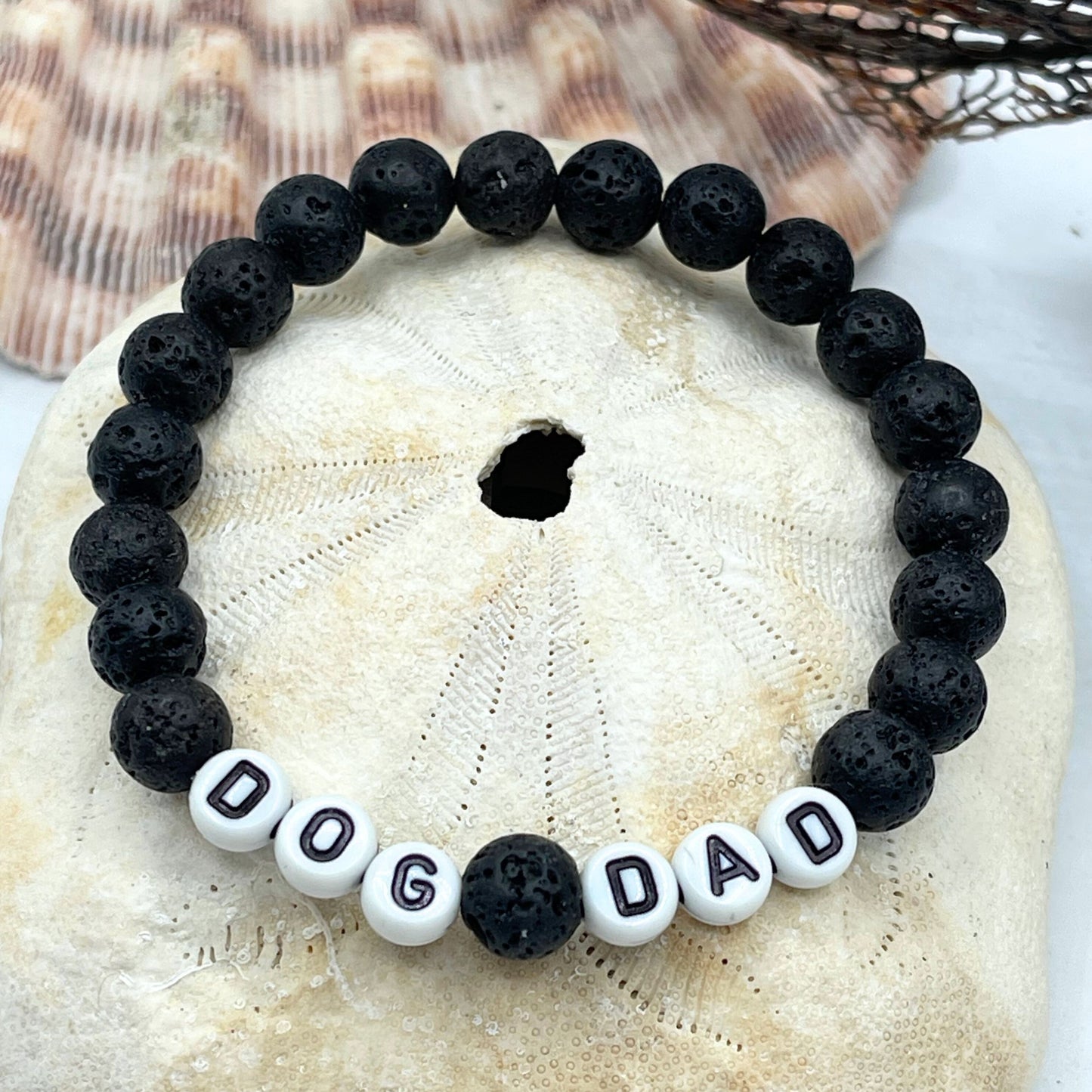 dog dad bracelet made of lava rock on a sand dollar