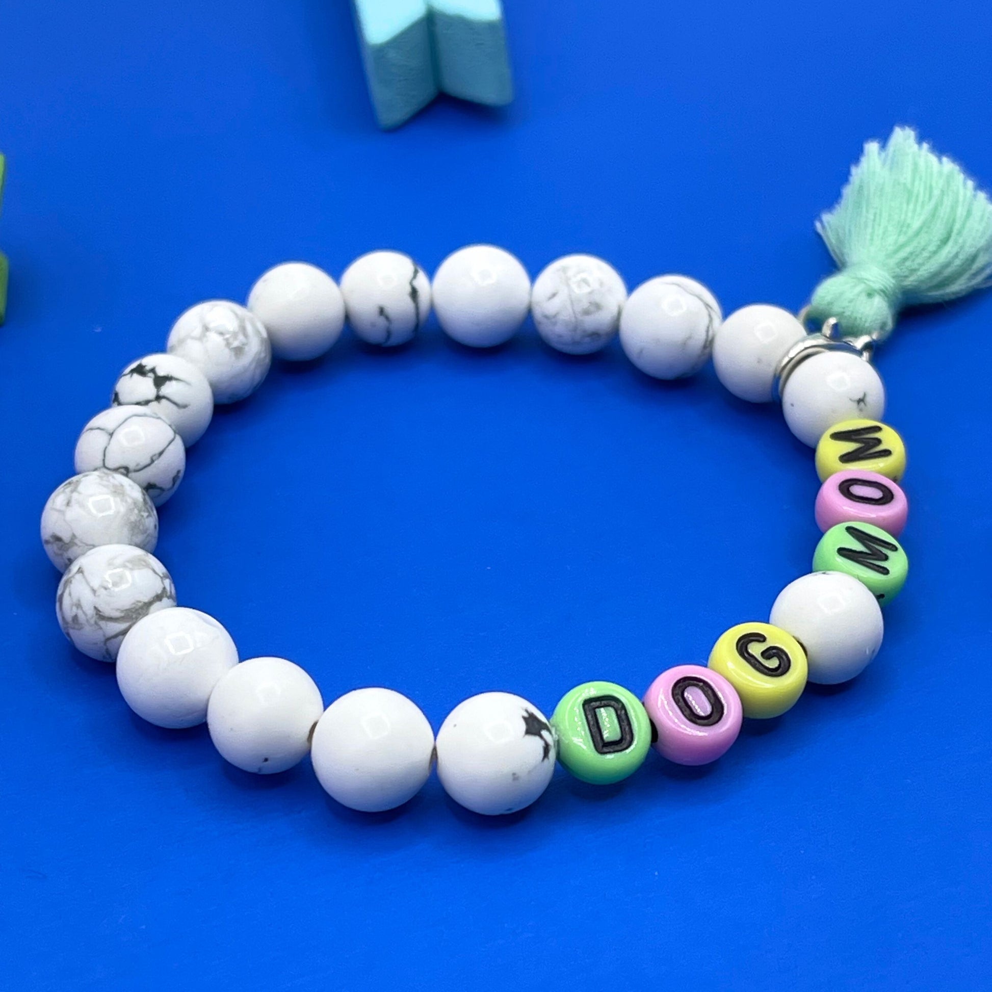 Our Howlite 8mm beaded bracelet says "Dog Mom” with detachable tassel (silver tone lobster claw), please let me know if you would like to change any of the wording. Each piece is made to order by me (Jessica) with love and the purest intentions.