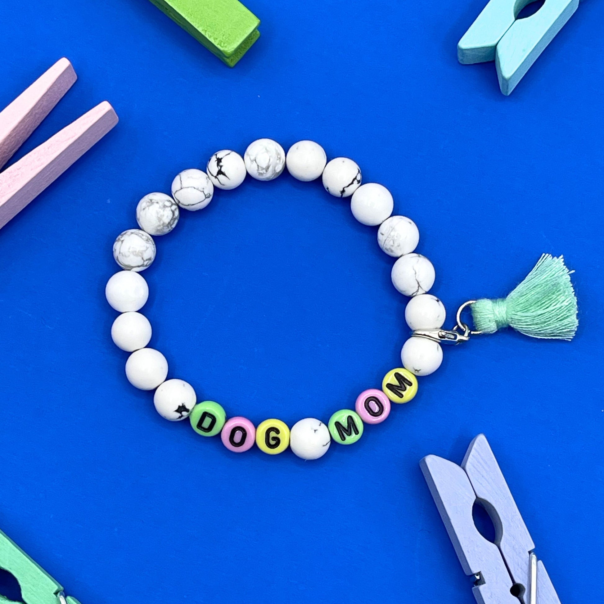 Our Howlite 8mm beaded bracelet says "Dog Mom” with detachable tassel (silver tone lobster claw), please let me know if you would like to change any of the wording. Each piece is made to order by me (Jessica) with love and the purest intentions.