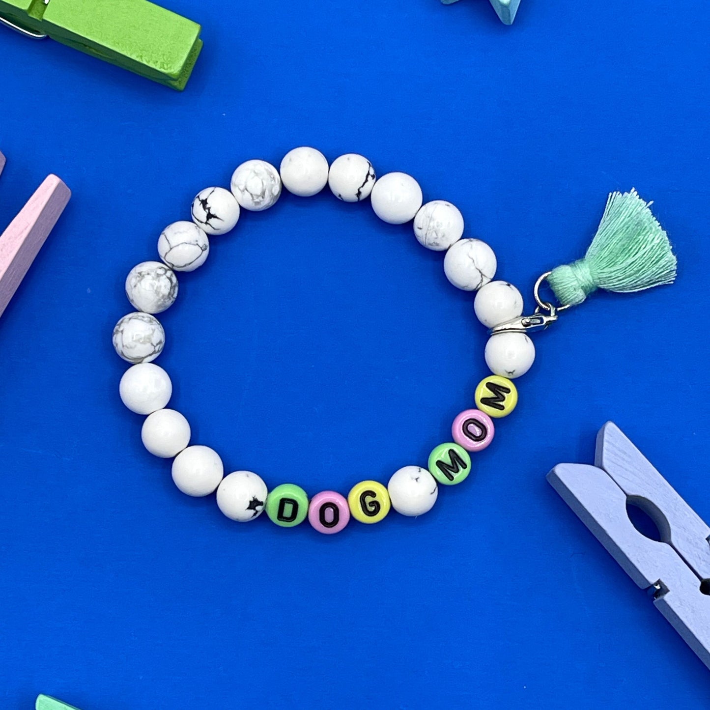 Our Howlite 8mm beaded bracelet says "Dog Mom” with detachable tassel (silver tone lobster claw), please let me know if you would like to change any of the wording. Each piece is made to order by me (Jessica) with love and the purest intentions.